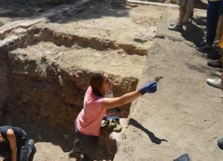 Una arqueóloga entrega un trozo de hueso recién hallado en el yacimiento.